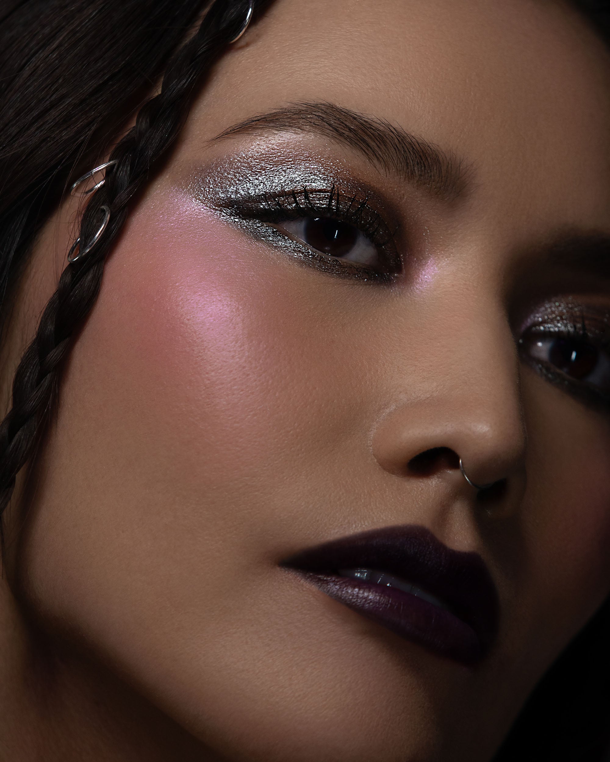 Close-up of a person with dramatic makeup and braided hair.