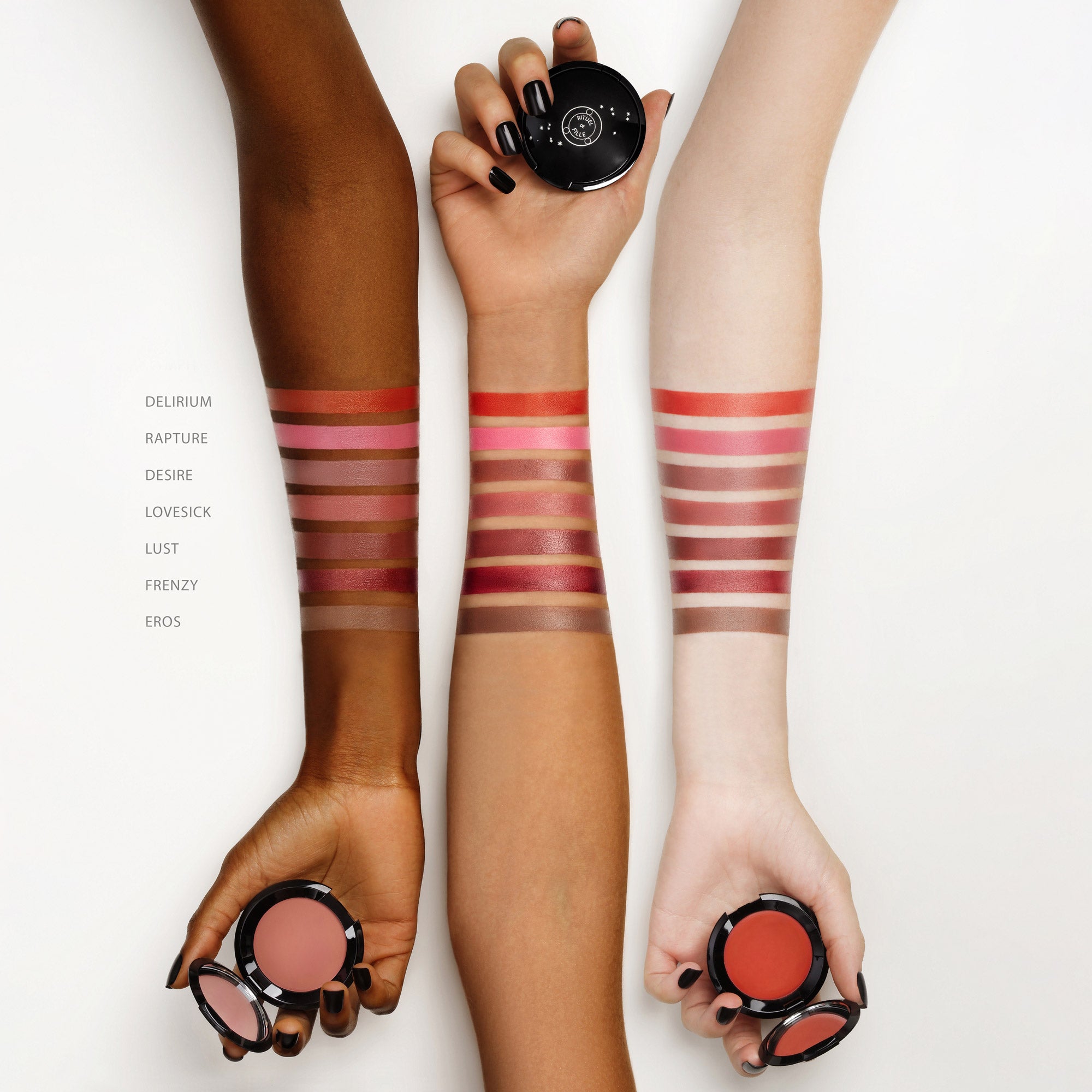 Three hands with makeup swatches on wrists holding a compact