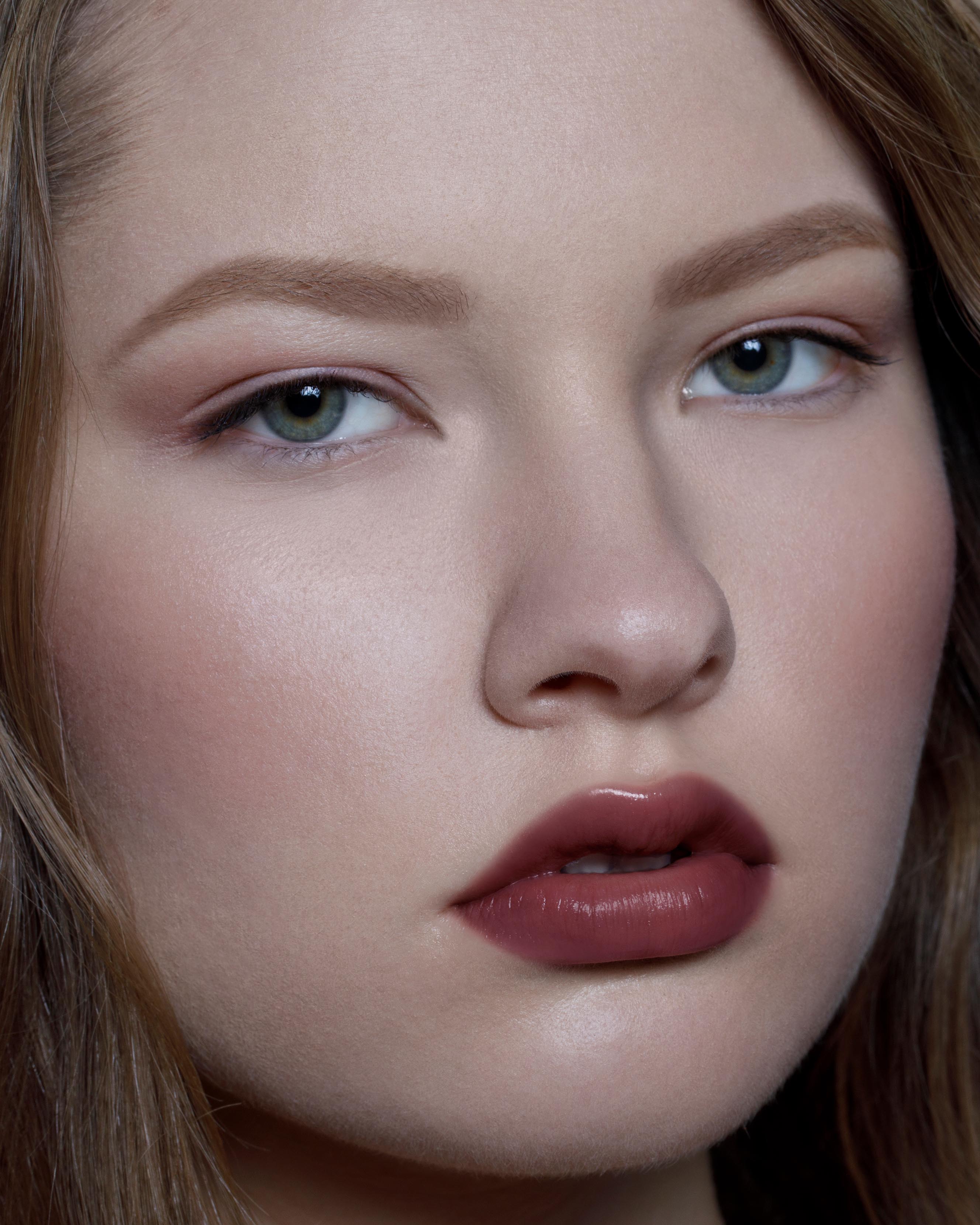 Close-up of a model with light skin wearing burgundy red makeup on lips, eyes, and cheeks